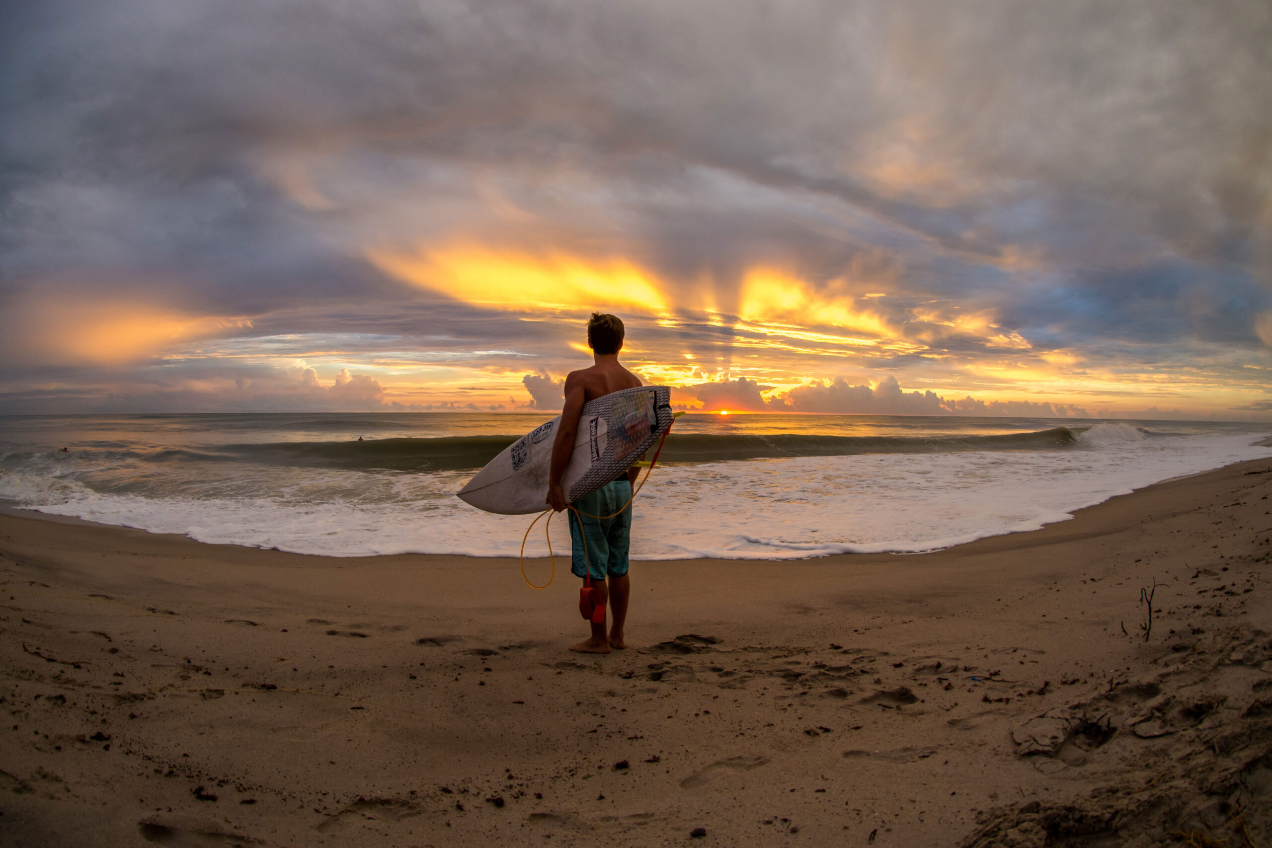 A surfer watches a beautiful sunrise in Cocoa Beach, FL