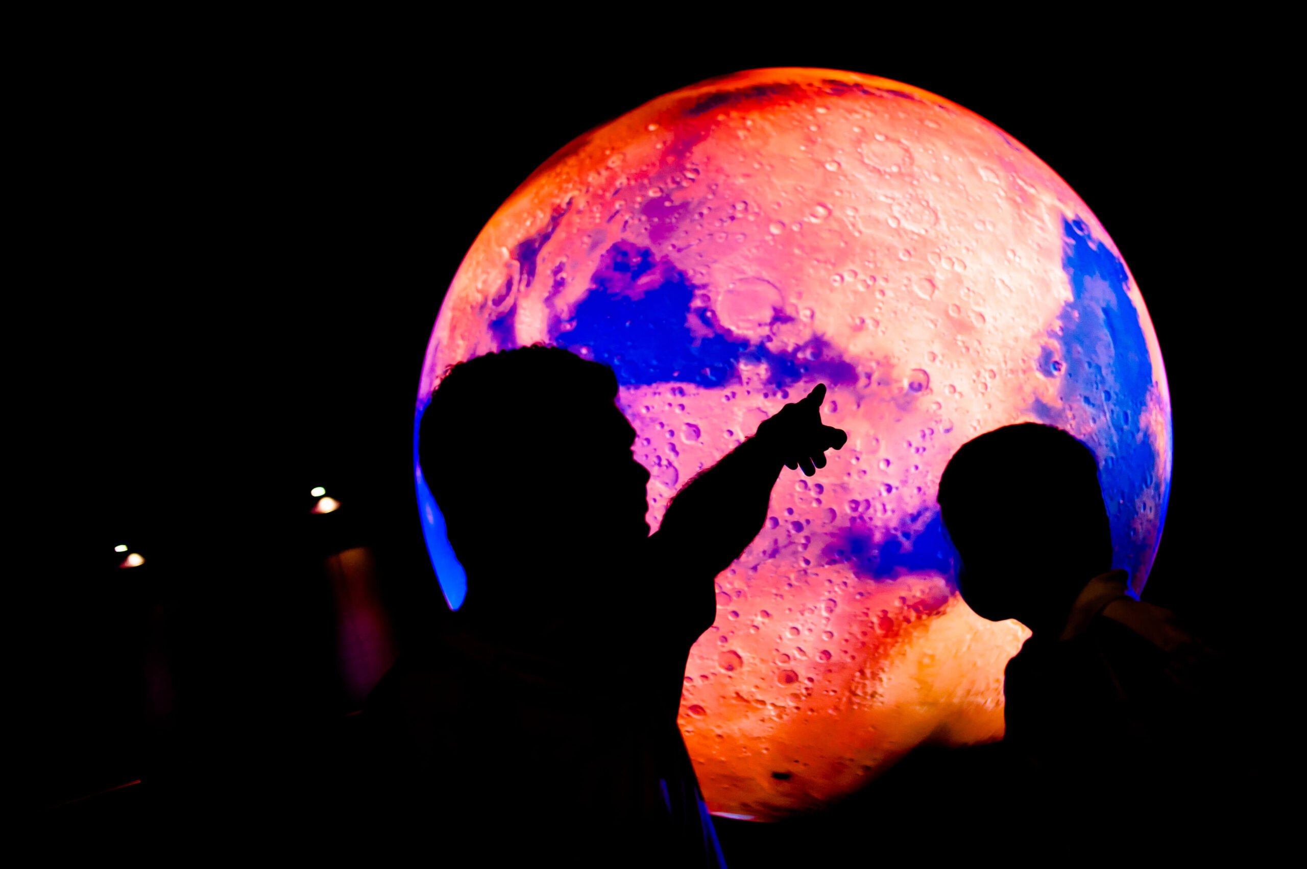 Silhouette of children pointing at a projection of the moon